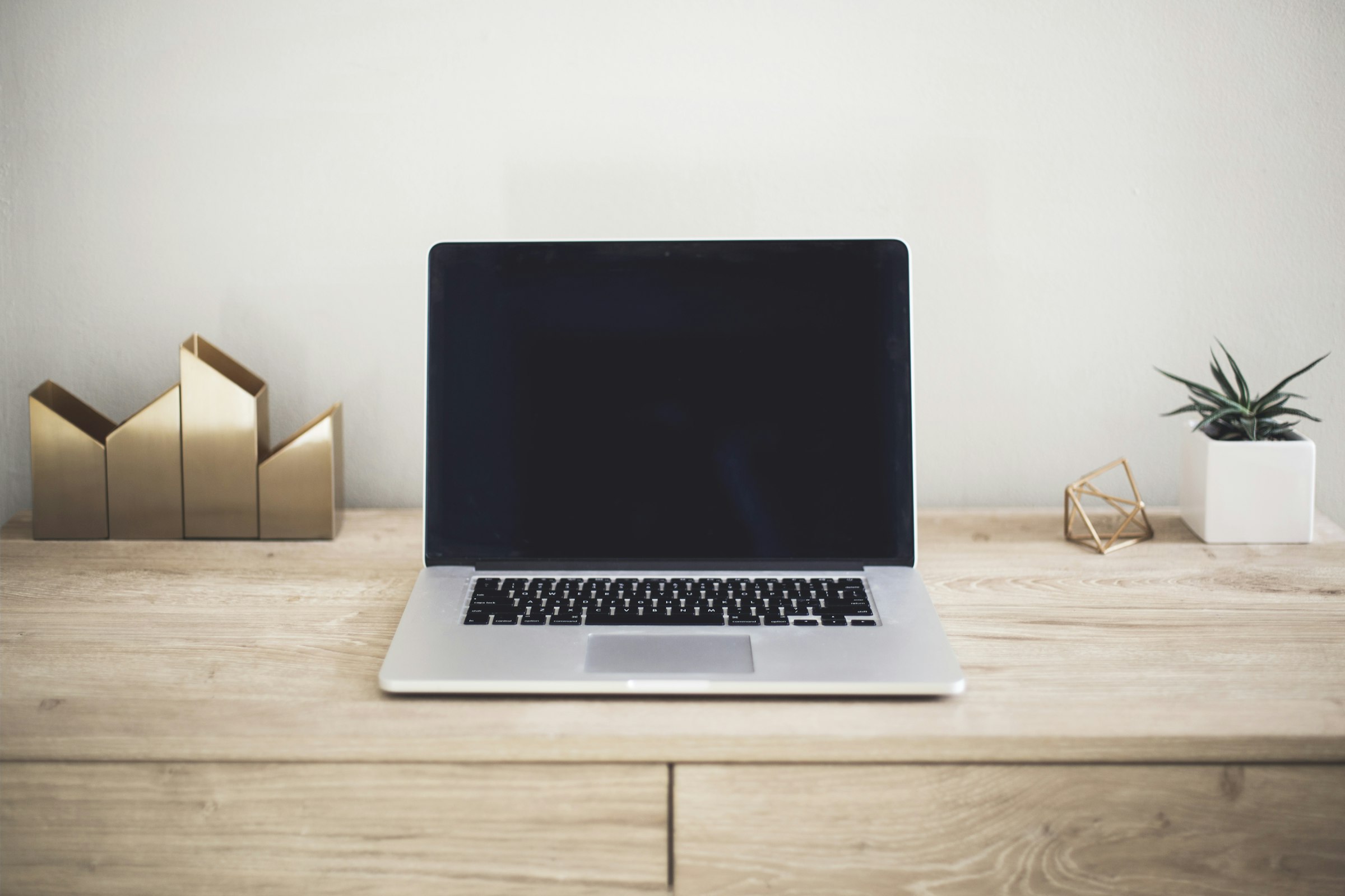 A laptop open on a plain wooden desk, showing the kind of quiet, ordinary desk the agent runs on in the background.
